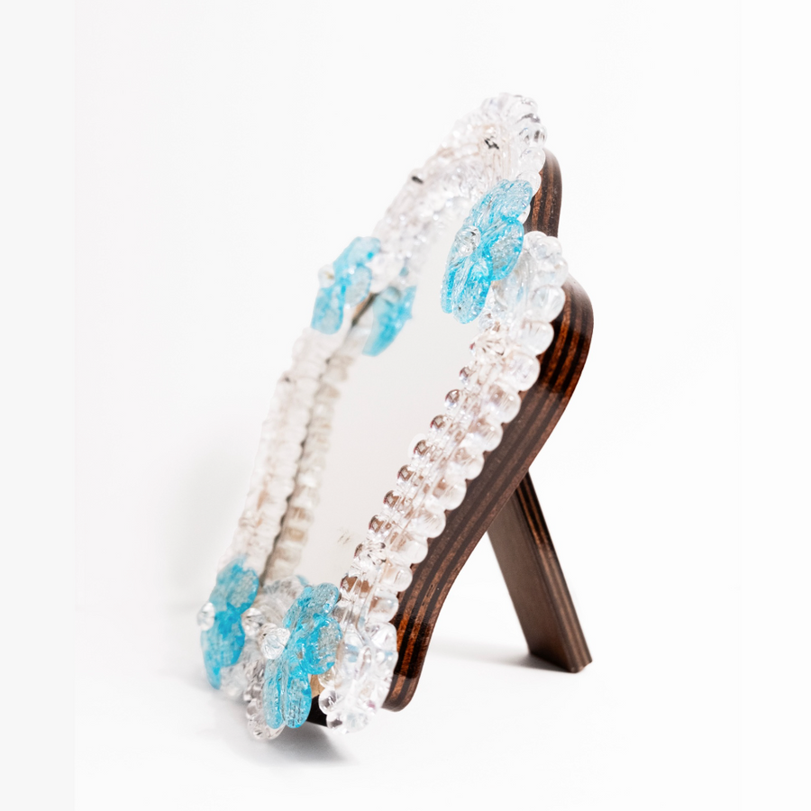 A side view of Anami Alchemia's ornate yoni viewing mirror in blue colour way, against a plain white background. 