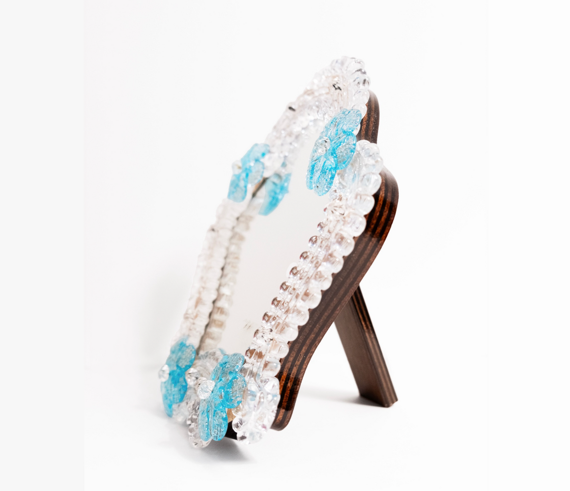 A side view of Anami Alchemia's ornate yoni viewing mirror in blue colour way, against a plain white background. 